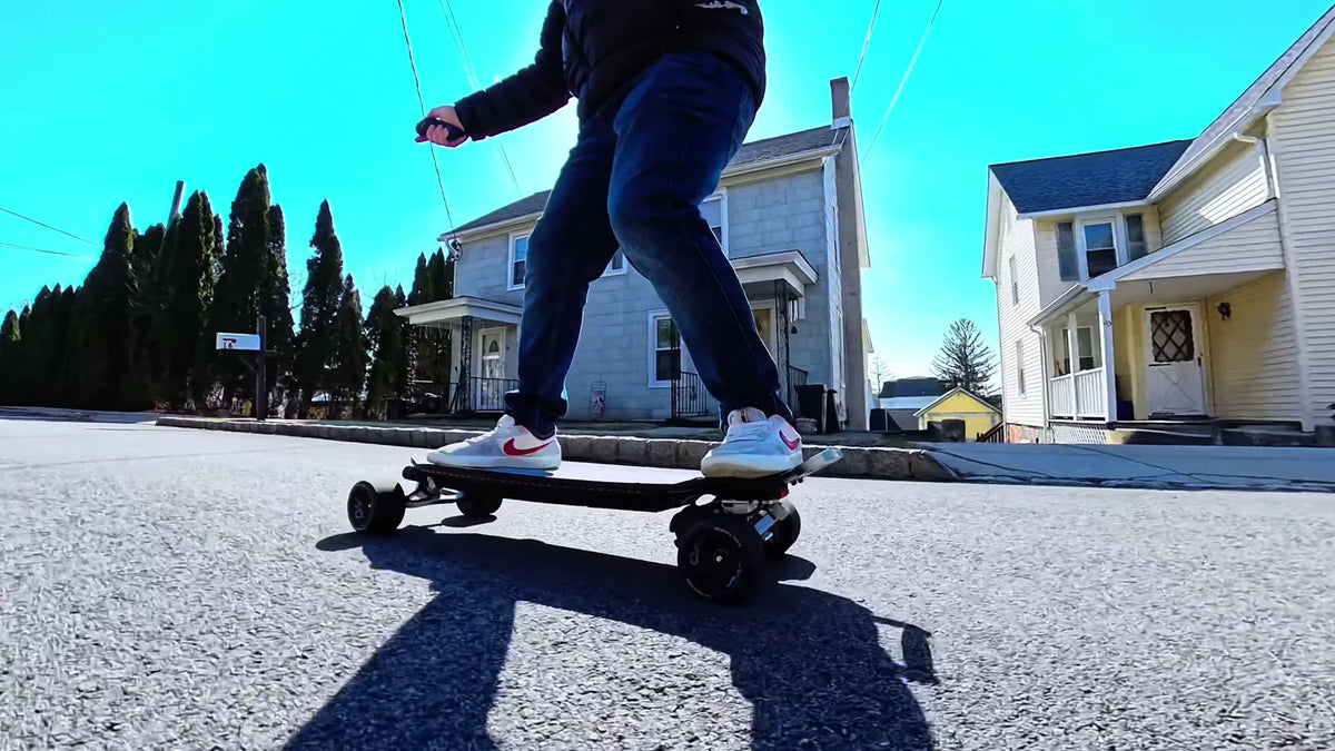 Rider performing a brake test on an OMW Gladius electric skateboard on dry pavement