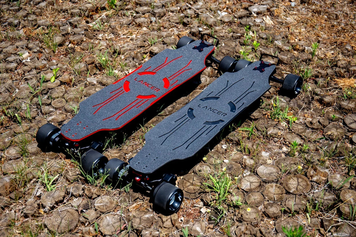 Two OMW Lancer electric skateboards with 105 mm street wheels in a dry outdoor setting