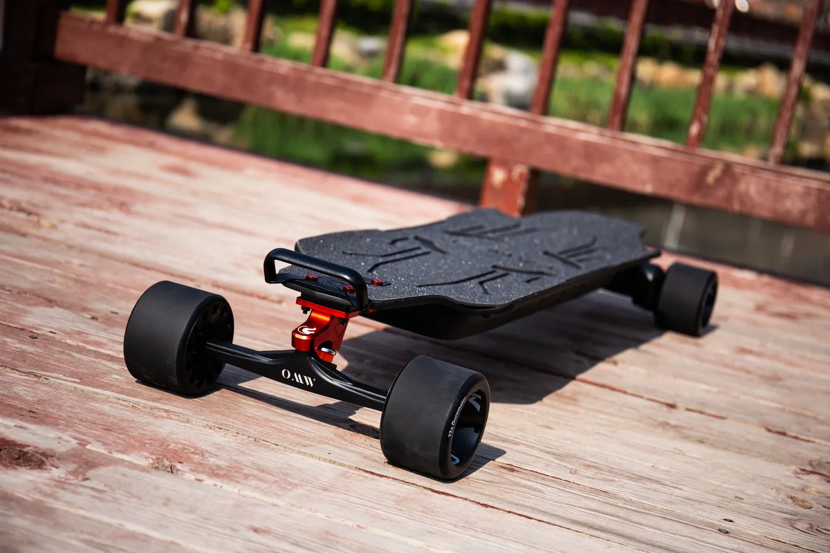 OMW Lancer electric skateboard with black deck and red truck detail on a wooden bridge
